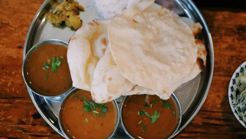 A vibrant overhead photograph of an elaborate Indian thali with dozens of colorful dishes arranged on a banana leaf