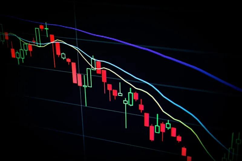 A dramatic visualization of the Indian stock market showing Sensex and Nifty charts with candlestick patterns against a backdrop of the Bombay Stock Exchange building